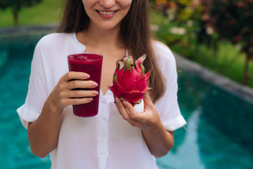 Wall Mural - Close up glass of dragon fruit smoothie and fruit in woman hands.