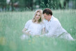 © yurolaitsalbert - beautiful pregnant woman with her husband sitting on lawn in summer day.