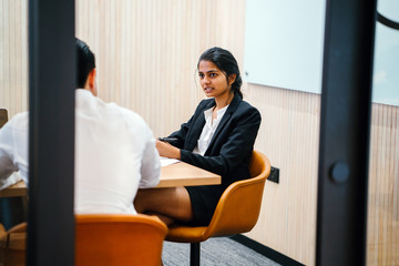 Wall Mural - An exquisite Indian woman sitting alongside an accomplice inside a meeting room. She is talking about some methodology and looking lovely in her office clothing.