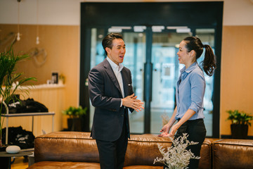 Portrait of two Asian Chinese business people in a corporate attire having a casual discussion in the office pantry during the day. They are having an animated conversation with hand gestures.