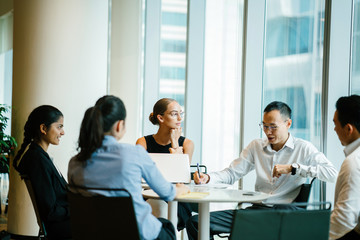 A group of professionals discussing a project inside a conference room. They are meeting up to finish a certain job in corporate attire and elegant dresses. 