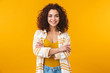 © Drobot Dean - Image of young woman 20s with curly hair smiling and standing with arms crossed