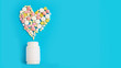 pills in a plastic jar on a blue background in the shape of a heart. free space for text.