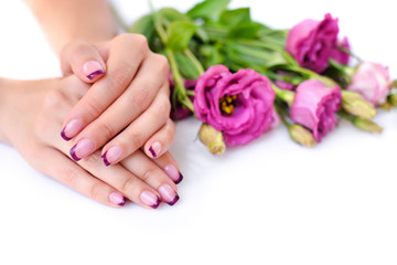 Wall Mural - Hands of a woman with pink french manicure and flowers eustoma on a white background