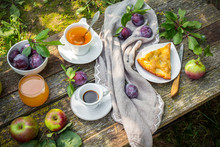 Lunch Breakfast On The Terrace In The Garden. Orange Juice, Pie, Coffee, Tea, Apples On A Wooden Table In The Garden.