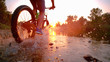 LENS FLARE: Sportsman riding his bicycle in the shallow stream towards sunset.