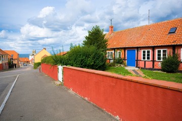 Sticker - Traditional colorful half-timbered houses in the street leading towards harbor during cloudy day, Hasle, Bornholm island, Denmark