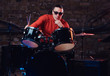 © Fxquadro - Young stylish musician in sunglasses sits behind the drum set against a brick wall, thoughtfully looking at the camera. Perform in a night club
