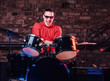 © Fxquadro - Emotional drummer plays at a night club performance against brick wall background. Photo with lighting motion effect