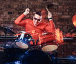 © Fxquadro - Young Stylish musician in sunglasses emotionally playing drums against brick wall background, perform in a night club. Photo with lighting motion effect