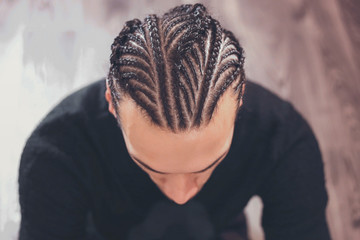 male hairstyle close-up braids, hair braided, pensive look, man portrait