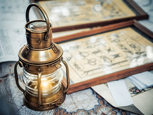 Old Brassy Ship Lantern Stands On A Map Of The Seas Near Pictures With The Image Of Sea Knots