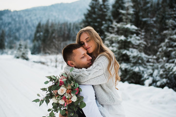 a couple hugging in the winter. boy and girl hug in the winter forest. boy and girl in the mountains