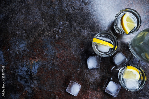 Cuadros en Lienzo Cold vodka in shot glasses with lemon on stone background