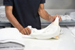 Elderly hands of caucasian male laundry hotel worker folds a clean white towel. Hotel staff workers. Hotel linen cleaning services.
