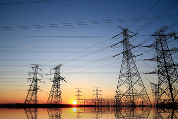 Wall Mural - A high-voltage tower in the setting sun against the sky