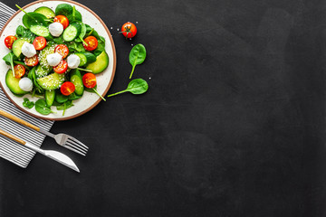 Wall Mural - Healthy lunch. Fresh vegetable salad on black background top view copy space