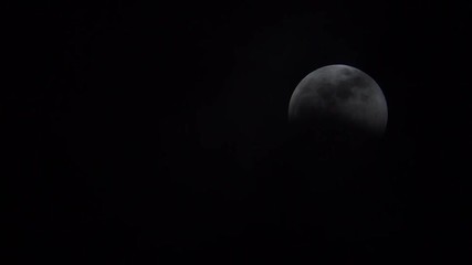 Wall Mural - thin, wispy clouds moving slowly to reveal a full moon during a lunar eclipse.