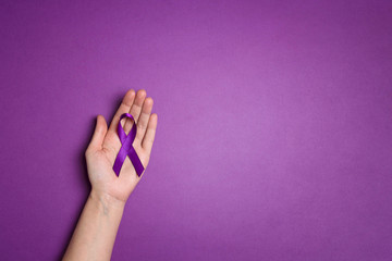 Wall Mural - Hand holding Purple ribbons on a p urple background. World epilepsy day.