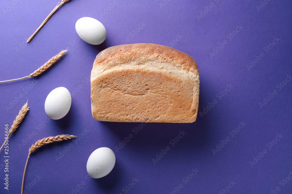 Tasty bread with eggs and wheat ears on color background
