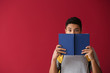 © Pixel-Shot - African-American schoolboy with book on color background