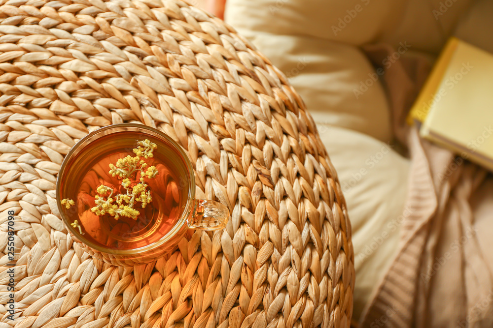 Cup of hot tea on wicker pouf