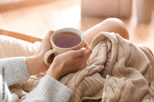 Young woman drinking hot tea at home, closeup © Pixel-Shot