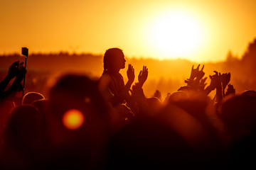 Wall Mural - Girls with hands up dancing, singing and listening the music during concert show on summer music festival, sunset