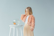 cute kid in faux fur coat and skirt looking at fishbowl on stool isolated on grey