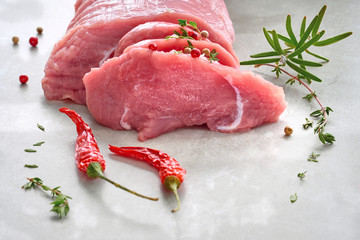 Close-up on slices of raw beef meat. Tenderloin with herbs and spices on stone board.