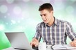© BillionPhotos.com - Happy young man works on his laptop with coffee at the table