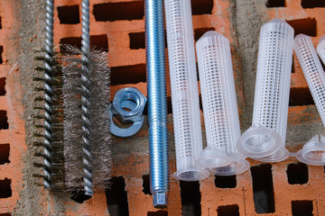  set of parts for mounting anchors in hollow brick and concrete lie on the surface of the brickwork in any order. Studs threaded, mesh sleeves. Brushes to clean the holes. Nuts, washers.