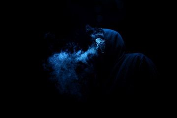 Man in black hood in the night darkness, dimly lit, concepts of danger crime, terror