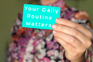 Wall Mural - text writing Your Daily Routine Matters on card holding by businesswoman