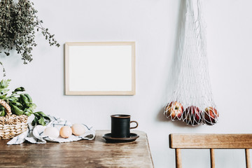 Stylish interior design of kitchen space with small table with mock up frame, herbs, cup of tea, bag with apples and vegetables. Vintage concept of kitchen space..