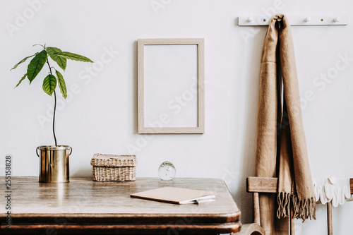 Vintage kitchen interior design with small table with mock up frame, straw boxes, avocado plant and notebooks. Minimalist interior.