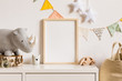 © FollowTheFlow - The modern scandinavian newborn baby room with mock up photo frame, wooden car, plush rhino and clouds. Hanging cotton flags and white stars. Minimalistic and cozy interior with white walls.Real photo