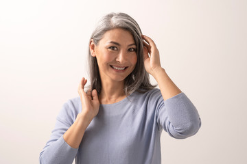 Wall Mural - Smiling Asian woman touches her grey hair