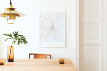 Stylish And Modern Dining Room Interior With Mock Up Poster Map, Sharing Table Design Chairs, Gold Pedant Lamp And Cups Of Coffee. White Walls,  Wooden Parquet. Tropical Leafs In Vase. Eclectic Decor.