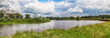 Panorama of the summer landscape with a view of the river and field. Fishing on a pond on a warm day, fishing rods and feeders are thrown into the water.