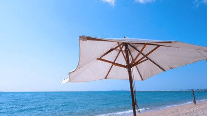 White fabric color texture beach umbrella and brown wood tripod with white cloud and clear blue sky summer sunlight day in low angle view camera for travel asia Thailand Pattaya.