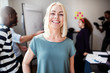 © Flamingo Images - Smiling designer standing in an office with coworkers behind her