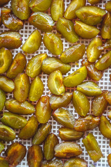 Sticker - sliced plums in a dehydrator dryer, close-up. View from above