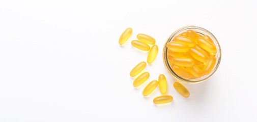 Omega 3 capsules in glass jar on white background Fish oil Yellow softgels Vitamin D, E, A supplement Banner