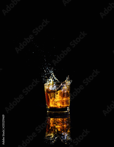 Fotomural Isolated shot of whiskey with splash on black background