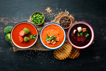 Colored vegetable soup cream. Dietary food. On a black background. Top view. Free copy space.