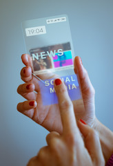 Woman hand holding transparent smartphone and touching the screen. Social media, business, technology and people concept