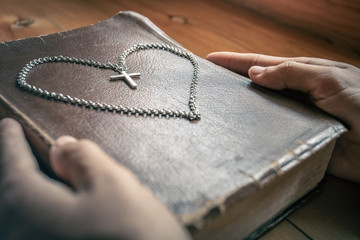 Canvas Print - Close up of man praying with cross necklace on the old holy bible. symbol of christian concept.