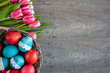 Wielkanocne tło z różowo-białymi tulipanami i koszykiem pełnym kolorowych pisanek 