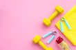 © 9dreamstudio - Fitness set with bars, towel, bottle of water and wrist builder on pink background top view mock up